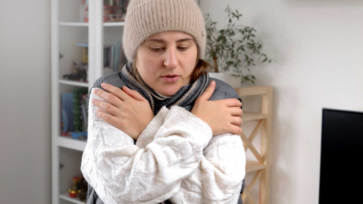 Closeup of woman shivering and dancing to warm up herself in cold house. Concept of energy crisis, high bills, economy and saving money on monthly utility payments